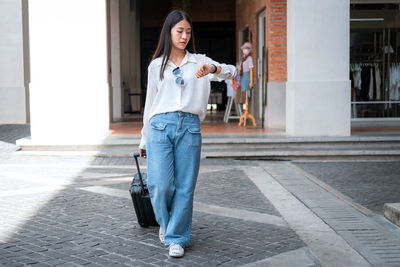 Full length of woman checking time outdoors