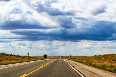 Empty road against cloudy sky