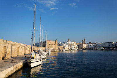 Boats in sea against clear blue sky