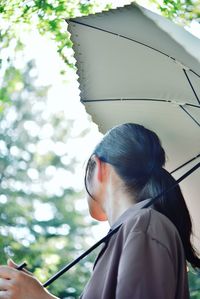 Young woman holding umbrella looking away standing outdoors