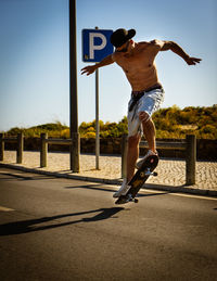 Full length of man skateboarding on sunny day