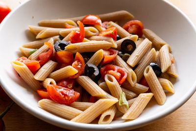 Italian pasta with tomato and olives. high angle view of fruits in container on table