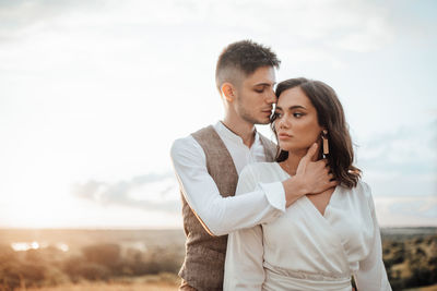 Young couple standing against sky