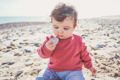 Cute girl holding pebble stone on beach