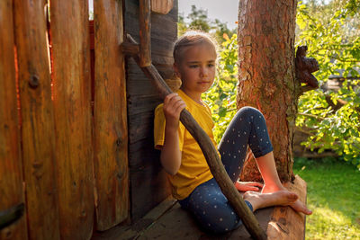 Girl plays in creative handmade treehouse in backyard, summer activity, happy childhood, cottagecore