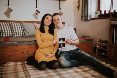Full length of smiling young woman sitting at home