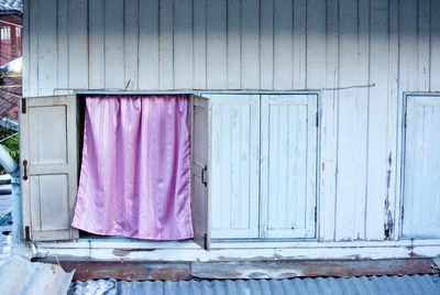 Pink curtain hanging on window of house