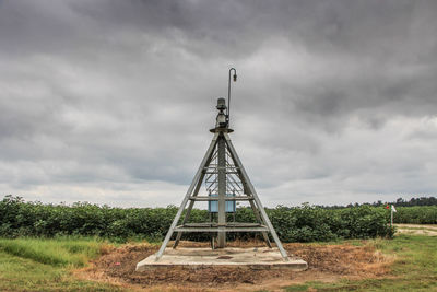 Traditional windmill on field against storm clouds