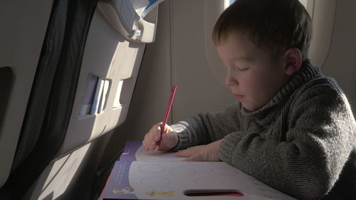 Boy doing homework at airplane