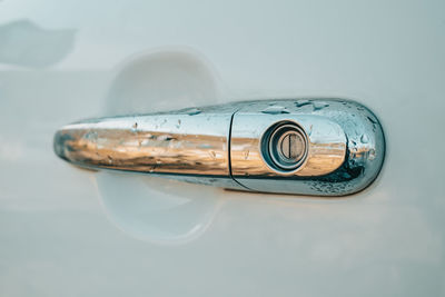 Close-up white car door handle with water drops during washing