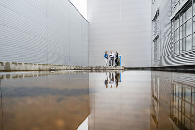 Coworkers with reflection on water in front of industrial building