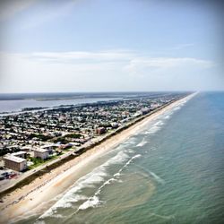 Aerial view of city by sea against sky