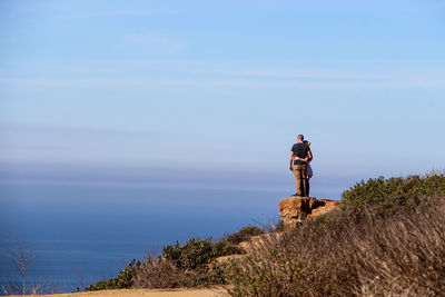 Couple standing on cliff against sea