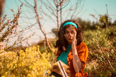 Woman with book standing by plants