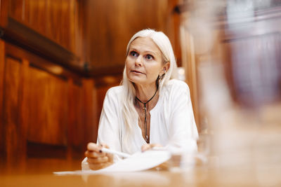 Confident businesswoman sitting with contract document in board room