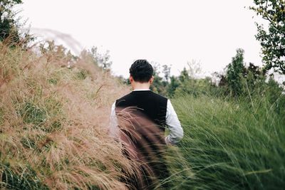 Rear view of man on field against clear sky