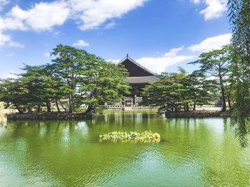 House by lake against sky