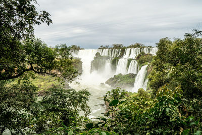 Scenic view of waterfall against sky