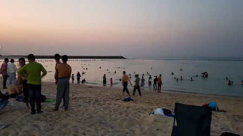 People on beach against sky during sunset