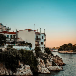 Buildings by sea against clear sky