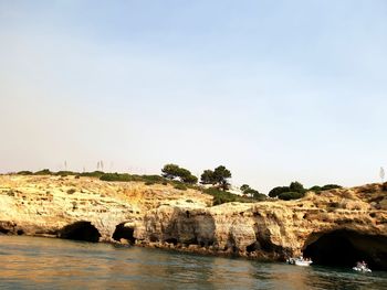 Rock formations by sea against clear sky