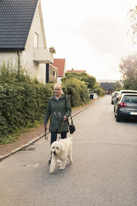 Mature woman with dog walking on street during sunset