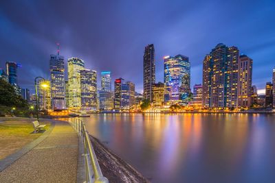 Illuminated city by buildings against sky at night