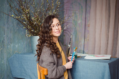 Portrait of beautiful young woman standing against wall