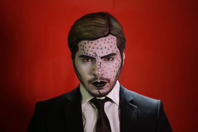 Close-up portrait of man with halloween make-up against red background