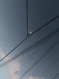 Low angle view of power cables against sky