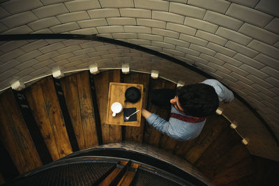 High angle view of waiter with tray moving up on steps in restaurant