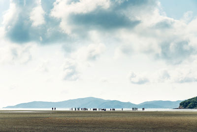 People on land by sea against sky