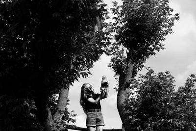Low angle view of woman standing against trees