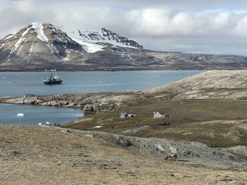 Scenic view of sea by mountains against sky