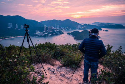 Rear view of man photographing at sunset