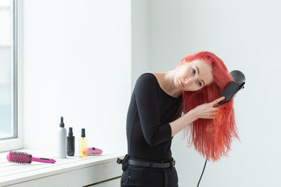 Portrait of woman holding red while standing at home