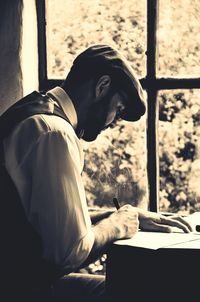 Side view of young man sitting on book