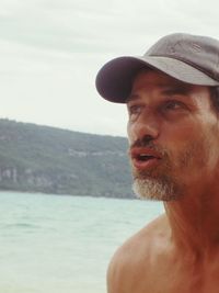 Portrait of shirtless man in sea against sky