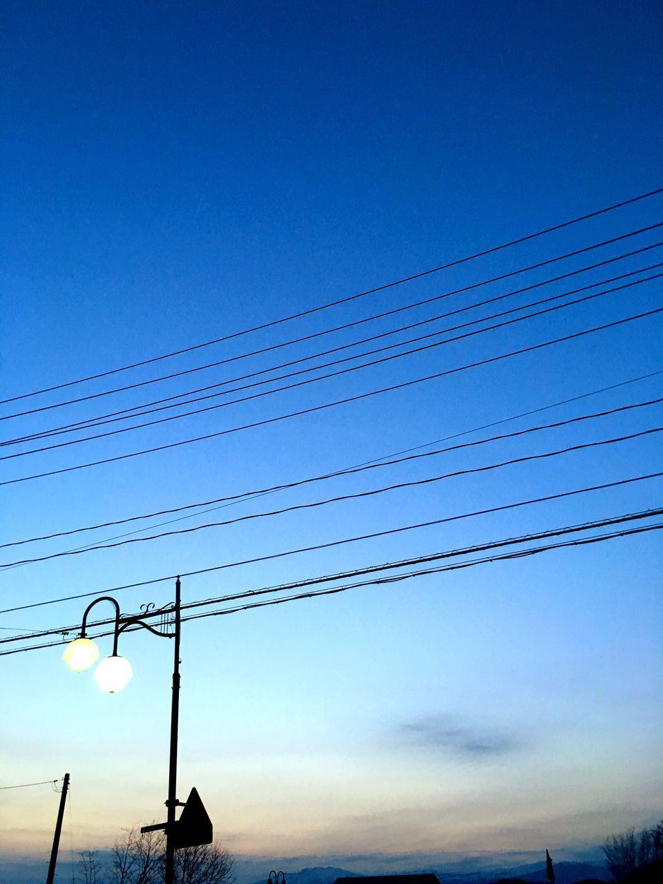 low angle view, silhouette, power line, electricity pylon, electricity, blue, connection, sunset, clear sky, power supply, sky, cable, fuel and power generation, dusk, tranquility, technology, nature, copy space, outdoors, beauty in nature