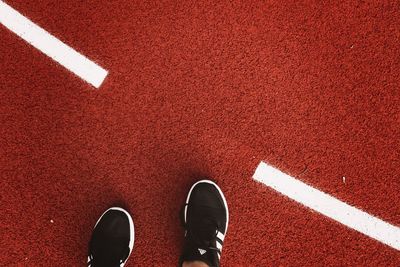 Low section of person wearing sports shoes on running track