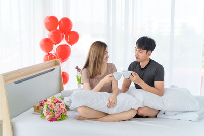 Young couple sitting on balloons at home