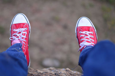 Low section of man wearing red canvas shoes