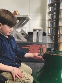 Boy looking at equipment while kneeling at cafe