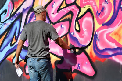 Rear view of man standing against yellow wall