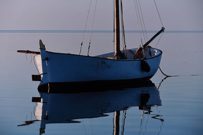 Sailboats moored in sea against clear sky