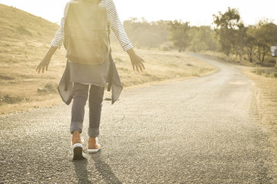 Rear view of woman walking on road