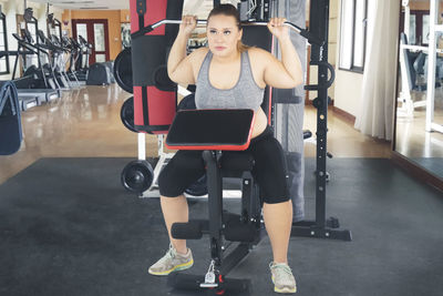 Overweight young woman exercising in gym