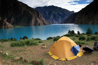 Tent on mountain by lake against sky