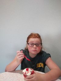 Portrait of boy sitting against wall at home