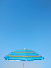 Low angle view of umbrella against blue sky